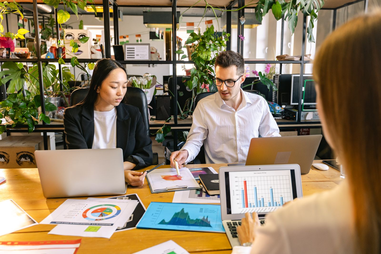 Trois collaborateurs analysent des documents et des graphiques autour d une table de bureau