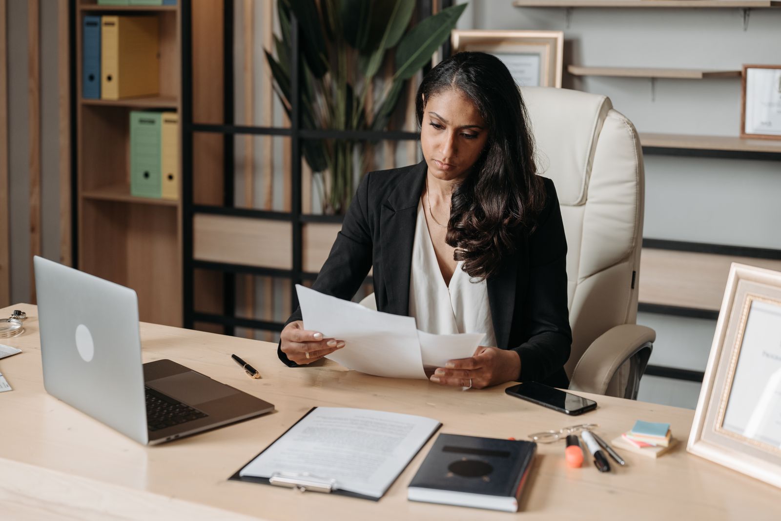 Une professionnelle examine des documents de paie à son bureau, devant un ordinateur portable